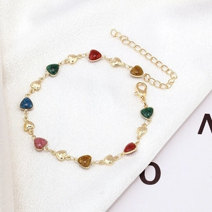 Close-up of heart-shaped charm bracelet with multi-color glitter and gold finish on silk