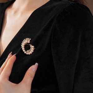 Close-up of elegant gold brooch with pink pearls and cubic zirconia on black velvet dress