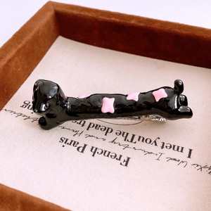 Detailed view of a black resin dachshund hair clip with pink bone pattern on a metal clip