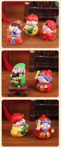 Group of colorful resin God of Wealth figurines on a wooden desk with bamboo decor