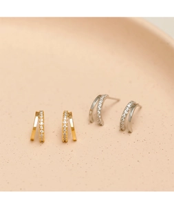 Detailed macro view of minimalist double-layer zircon stud earrings in gold and silver