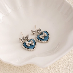 Detail of silver heart earring with blue denim fabric, pearls and shiny crystals