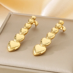 Detail of five golden hearts linked in a drop earring design on silk fabric