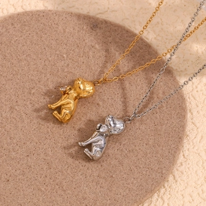 Flat lay of gold and silver puppy pendants on chains over textured fabric backgrounds