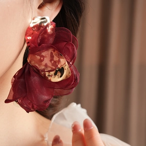 Close-up of model wearing burgundy chiffon flower earrings with elegant gold metal details