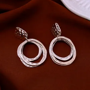Silver layered hoop earrings with hammered texture finish on red silk background