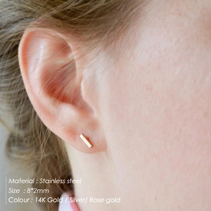 Close-up of minimalist 8x2mm stainless steel bar stud earrings worn on a model ear