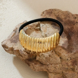 Eleganter Haargummi mit goldenem Metall-Bambusgelenk auf einem Naturstein-Hintergrund