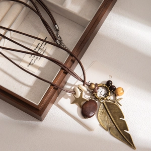 Detail of vintage bohemian necklace with bronze feathers and stars on a dark box