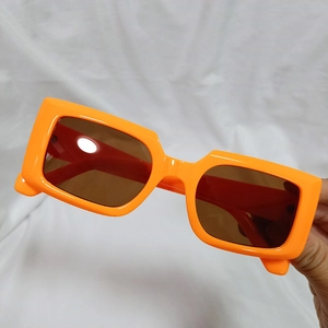 Detail of orange retro round frame sunglasses with brown lenses on white fabric