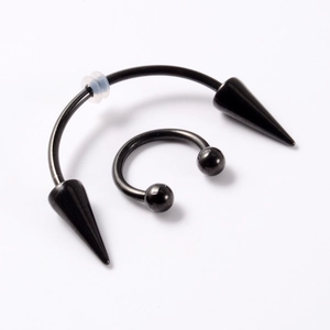 Detail view of black stainless steel horseshoe rings with spike and ball ends on white background