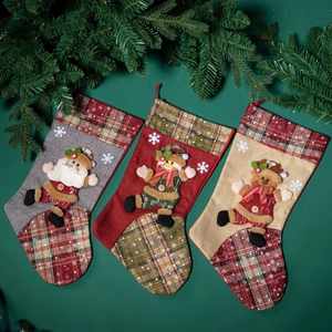 Three linen Christmas stockings with Santa, Snowman, and Reindeer on a green background