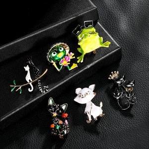 Detail showing a collection of colorful enamel cat and frog animal brooches on dark texture