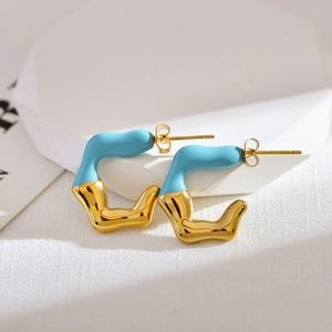 Detail of gold-plated stainless steel C-shape earrings with blue enamel lava design