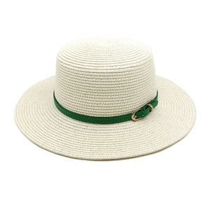 Détail du chapeau de paille blanc montrant la texture tissée et la ceinture en cuir vert