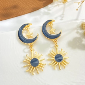 Vintage sun and moon drop earrings with blue enamel finish on white ceramic display
