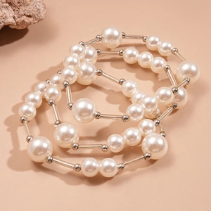 Détail macro du collier multi-rangs avec perles crème et tubes métalliques argentés
