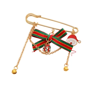 Detail view of a gold Christmas pin with red-green bow, Santa charm, and jingling bells