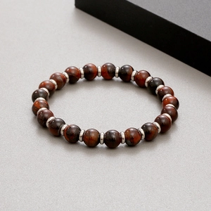 Detail of red tiger eye beads with silver metal spacers on a flexible bracelet