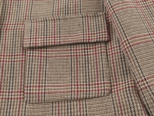 Macro view of plaid blazer fabric with pocket detail and precision stitching craftsmanship
