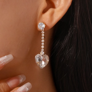 Macro view of long tassel earrings with sparkling heart-shaped cubic zirconia and gold finish