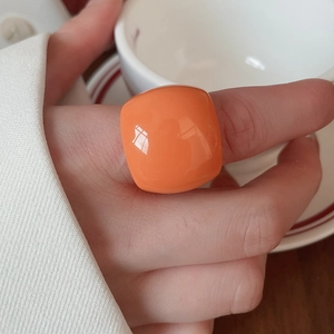 Close-up of a chunky orange resin geometric square ring worn on a person's finger