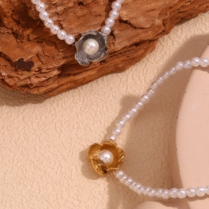 Detail of gold and silver flower pendants with pearls on beaded necklaces on wood