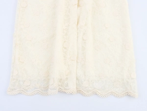 Gros plan sur tissu en dentelle blanche avec broderie florale et ourlet évidé ondulé