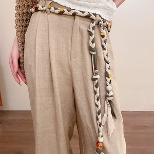 Detail view of ethnic hand-woven waist belt with resin beads on khaki trousers