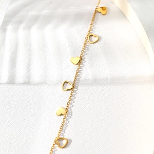 Détail d'un bracelet en acier inoxydable plaqué or avec pendentifs en forme de cœur