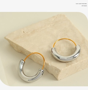 Close-up of geometric gold and silver two-tone hoop earrings on a stone plate