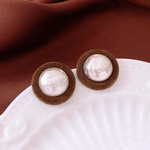 Close-up of vintage round plush earrings with dark brown fabric and textured silver center