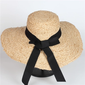 Close-up of a raffia straw sun hat featuring a wide brim and elegant black bow decoration