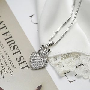 Silver crown heart pendant necklace with shimmering cubic zirconia on white silk