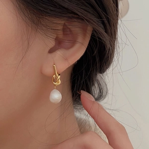 Close-up of a 925 sterling silver knotted pearl earring worn on a model's ear