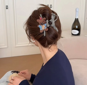 Detail of cute brown plush puppy and black white plaid bow hair clip on model's hair