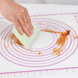 Silicone baking mat detail showing non-stick surface and measurement markings with scraper.