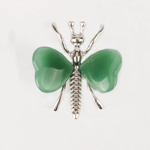 Detailed view of silver butterfly wings craft with green heart crystal stone inlay