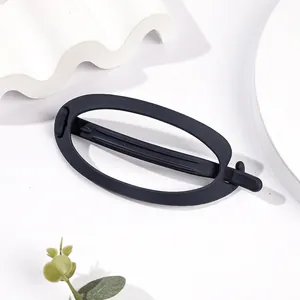 Detailed view of large black matte hair claw clip with elegant oval cutout on white pedestal