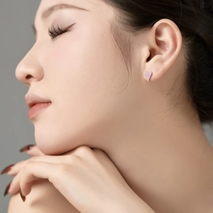 Close-up of pink heart-shaped stud earrings with sparkling crystals worn by a model