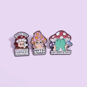 Whimsical mushroom and frog enamel pins set on a purple background with funny text