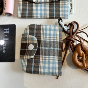 Close-up of vintage plaid fabric coin purse with white snap closure on a wooden desk
