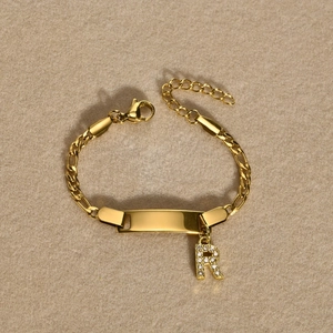 Close-up of golden stainless steel Cuban bracelet with rectangle ID plate and letter R charm