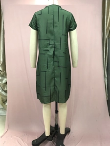 Detailed macro view of the green fabric with black geometric patterns on the midi dress