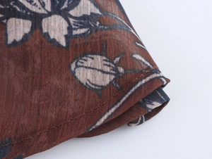 Macro view of red floral chiffon fabric with detailed hem stitching and botanical prints
