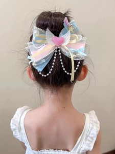 Detailed view of large organza bow hair clip with lace heart, wings and pearl tassels