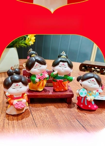 Detailed view of four Tang dynasty style girl figurines as creative keychains on wood