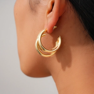 Close-up of triple layered gold hoop earrings worn by a model for a stylish vintage look