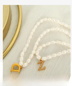 Detailed close-up of irregular pearl necklace with gold letter D and Z pendants