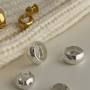 Close-up of chunky gold and silver 925 sterling silver hoop earrings on white knit